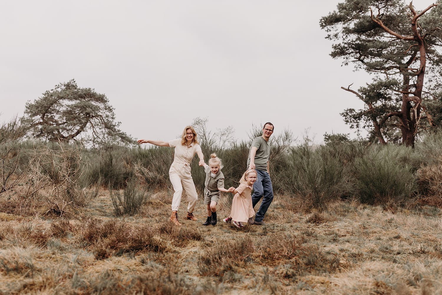 Speelse foto van een gezin in pastelkleuren tijdens een gezinsfotoshoot op de hei in Huizen, 't Gooi