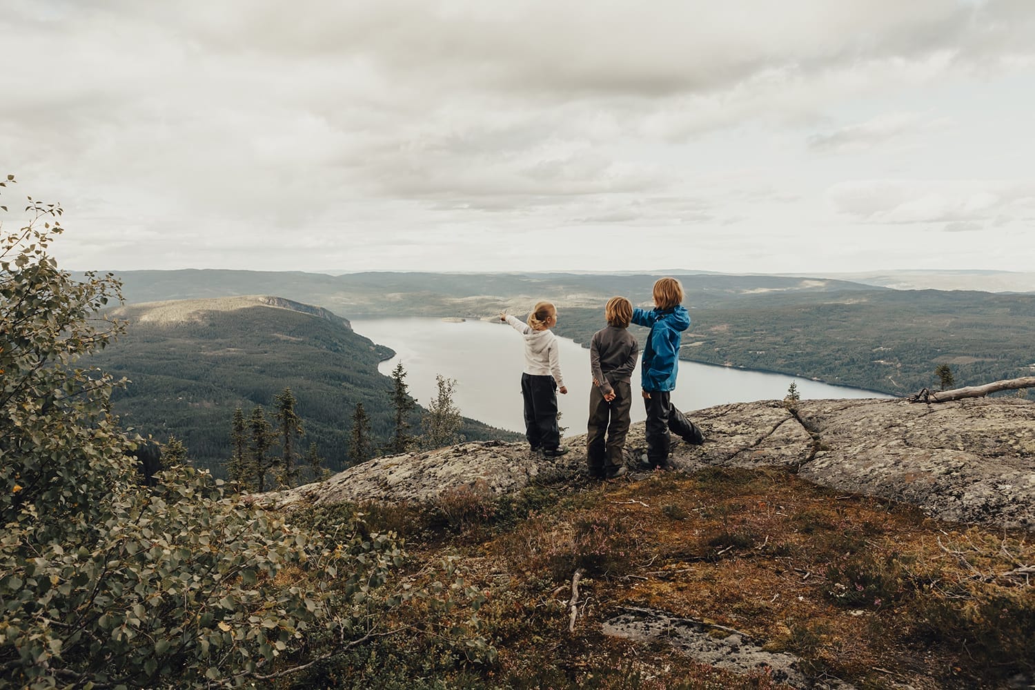 Kinderen op een bergtop met uitzicht over een Noors fjord — lifestyle fotografie Noorwegen